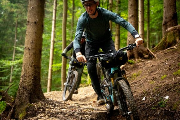 MTB Bike Station - Downhill Enduro - Santa Ponca Mountainbiker fährt einen schmalen, erdigen Pfad durch einen Wald.